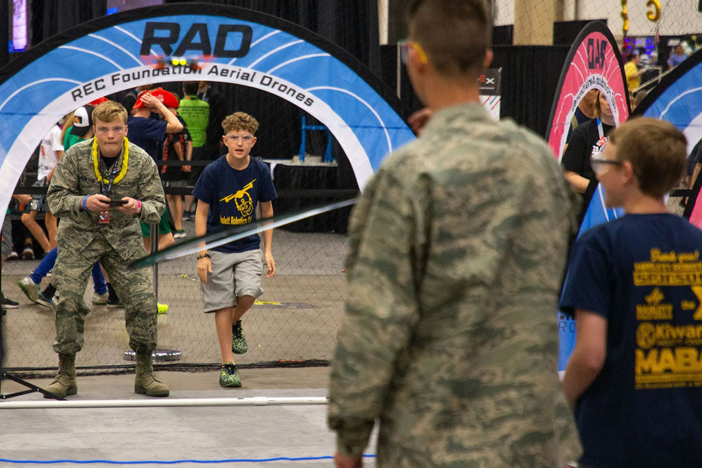 Students at Aerial Drone Competition flying drone under an arch