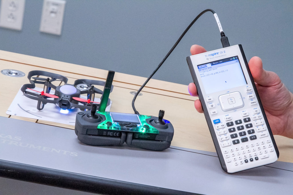 CoDrone EDU with Cable for TI Nspire CX II plugged into the calculator and controller. Hand holding the calculator.