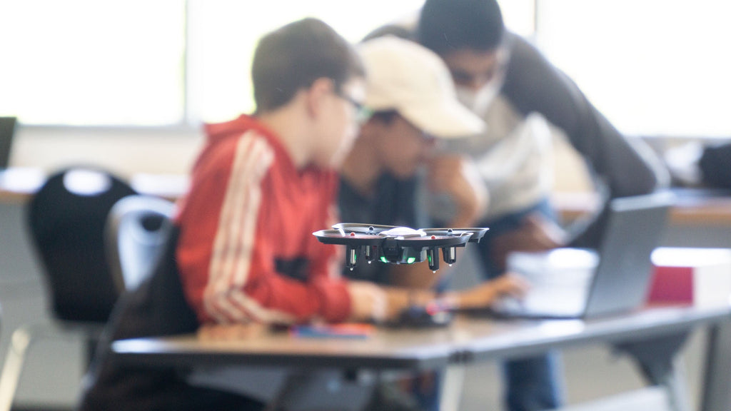 CoDrone EDU flying with students working in the background