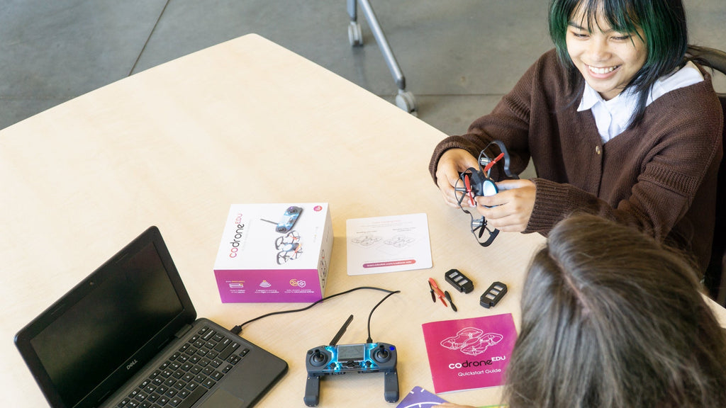 Student and teacher working on the CoDrone EDU at a table, with items unboxed