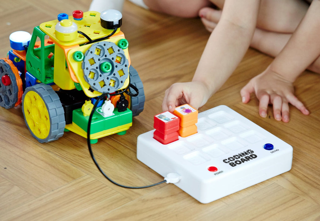 Buildy Bots with Coding Board on the floor, hand holding coding block